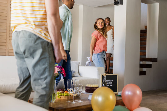 Friends celebrating new job with balloons and snacks, smiling and chatting happily