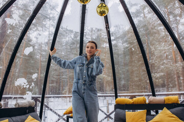 A woman is relaxing inside a domed tent at a glamping in the forest