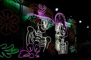 A large sign with skeletons and flowers on it. The skeletons are wearing hats and the flowers are...