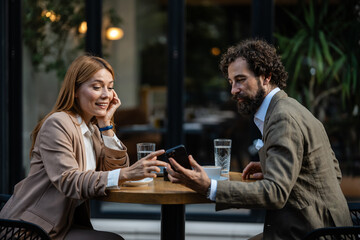 Business people using smartphone and talking at outdoor cafe