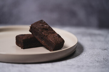 Close-up of Chocolate Brown on a smooth ceramic tile with soft natural light and a neutral stone background.