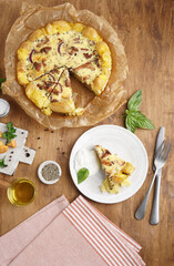 Homemade smash potato quiche with chanterelles and parsley cut on the table with slices on a plate top view