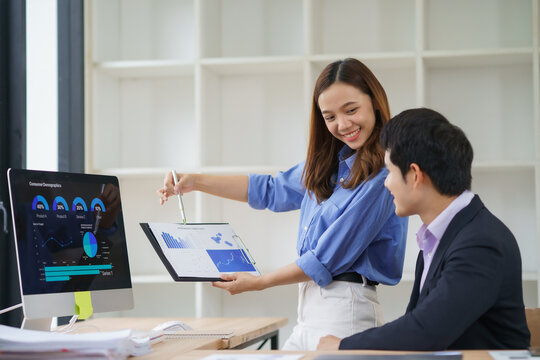 Asian business partners analyzing financial charts and graphs showing market growth, discussing company's performance and new business strategies