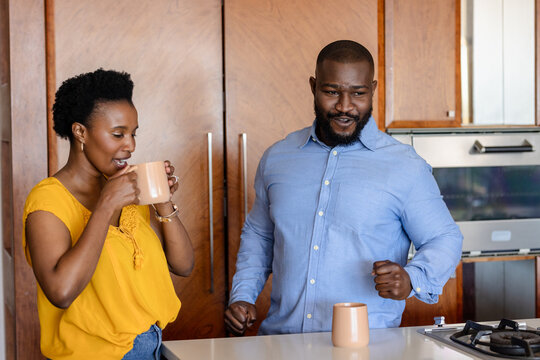 Couple enjoying morning coffee together in modern kitchen, sharing joyful moment - Powered by Adobe