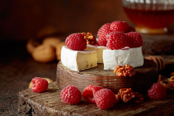 Camembert cheese with fresh raspberries, honey, and walnuts.