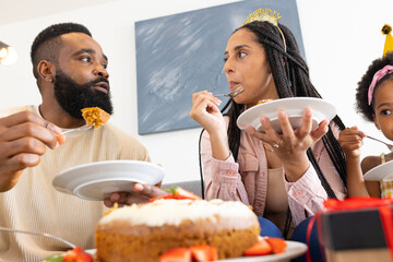 Family enjoying cake together at home, celebrating with smiles and laughter
