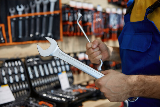 Man is holding a spanner in his hand inside a workshop