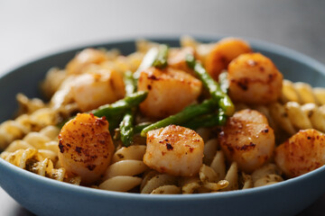 Fusilli pasta with scallops and asparagus in blue bowl closeup
