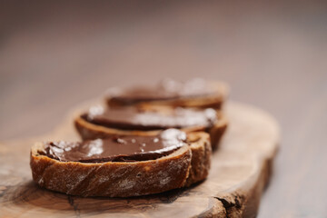 Ciabatta slices with chocolate spread on olive wood board