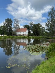 house by a pond with reflections and Lilly pads 