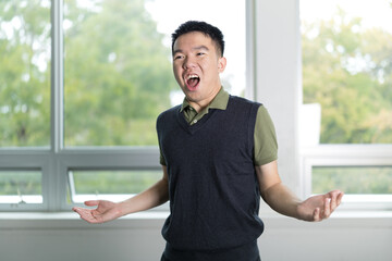 Young man speaking with expressive hand gestures and open mouth, as if delivering a passionate speech or presentation in class.