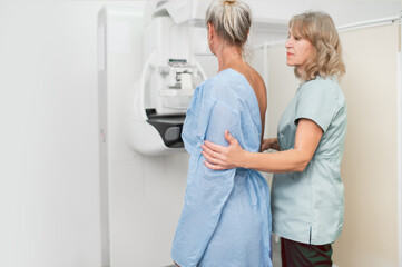 Fototapeta premium woman patient undergoes mammography procedure on mammograph digital mammography machine in modern clinic with doctor. Regular medical examination, screening for breast cancer 