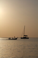Sunset on tropical island sea beach Thailand, calm ocean sunrise landscape, fisherman boat, ship silhouette, golden sun glow reflection, colorful sky clouds, summer holidays, vacation, travel