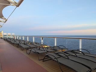 Open deck with empty sunbeds during sunset onboard a cruise ship