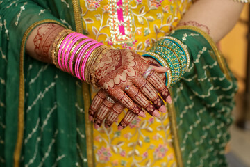 Henna-adorned hands with bangles and traditional attire