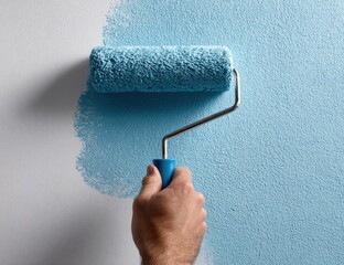 A hand holds a paint roller, applying light blue paint to a wall