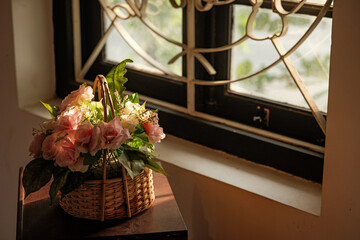 Decorative flower basket with pink roses by the window