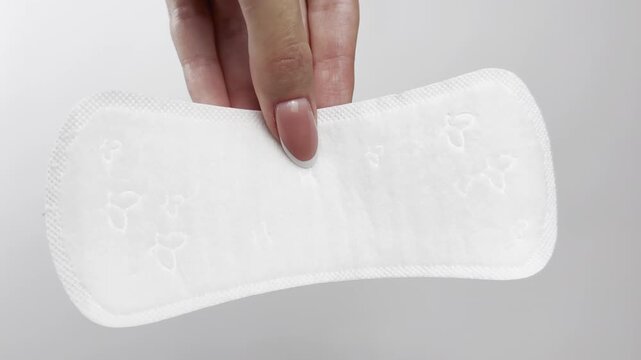 Female hand holding daily panty liner on white background, close-up. Feminine hygiene product for everyday freshness, women&rsquo;s health, menstrual cycle, gynecology, clean lifestyle, medical protection