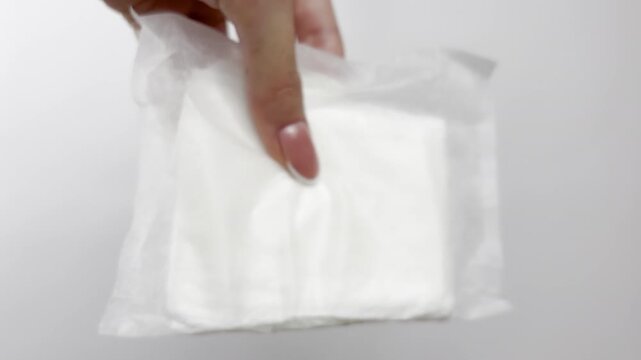 Female hand holding sanitary pad on white background, close-up. Feminine hygiene product for menstruation, women&rsquo;s health, period care, gynecology, clean lifestyle, medical protection