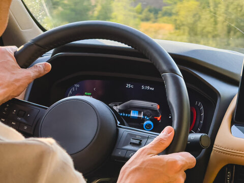 Close-up of hybrid vehicle steering wheel with energy flow display on dashboard