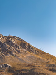 Wide mountain slope under clear sky with ski lift poles