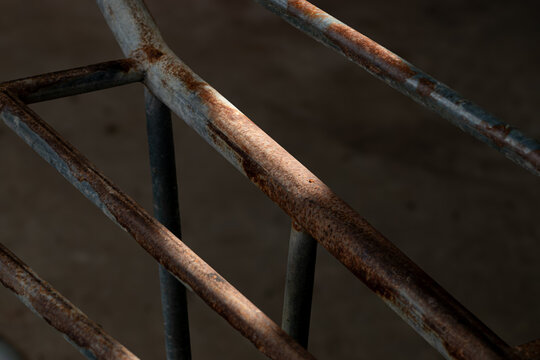 An abstract photo of old, rusty metal bars in the dark, with a sunbeam creating a highlight. - Powered by Adobe