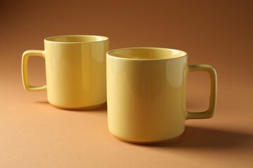 Promotion. Two yellow mugs on brown background
