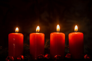 Four Advent red candles burning in dark background, fir branches and Christmas zero waste decorations. Holiday preparation copy space for text. Catholic traditions of Christmas new year winter