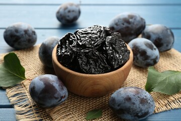 Dried prunes and fresh plums on blue wooden table, closeup