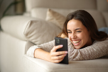 Happy woman laughing watching online content on mobile phone