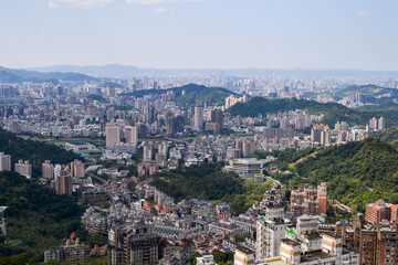 Obraz premium High-Density Urban Landscape Nestled in Lush Green Mountains Representing Sustainable City Planning and Real Estate Growth