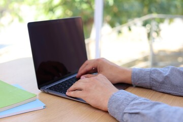 Fototapeta premium Man working on laptop at wooden table indoors, closeup