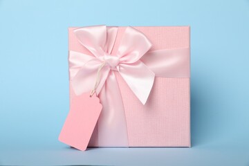 Gift box with blank tag on light blue background