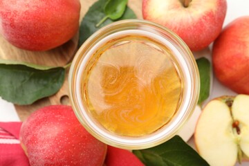 Fresh cider in glass, apples and green leaves on table, flat lay