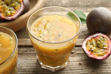 Tasty passion fruit drink and fresh fruits on wooden table, closeup