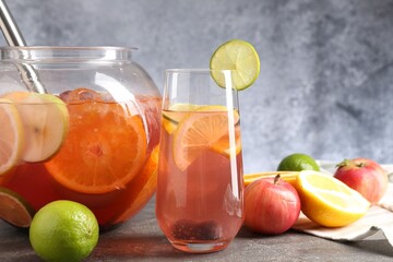 Punch and fresh fruits on grey table, closeup. Refreshing drink
