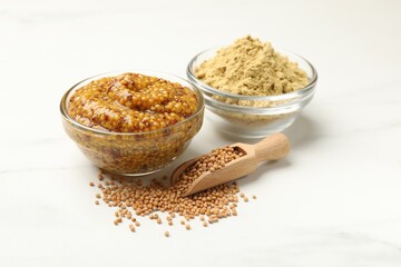 Different types of mustard on white marble table, closeup