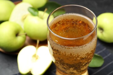 Fresh cider in glass and apples on table, closeup