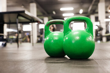 Green kettlebells on floor in gym, closeup. Space for text