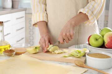Making delicious apple strudel. Woman cutting fresh fruit at white marble table in kitchen, closeup