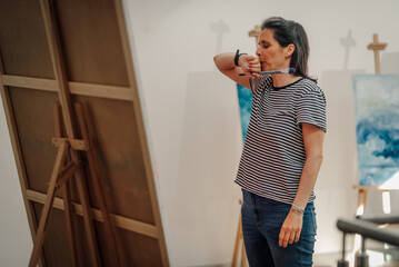 Female artist contemplating her work in progress in art studio