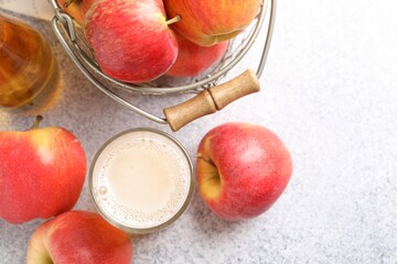 Delicious cider in glass, bottle and apples on light grey table, flat lay. Space for text