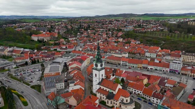 Cinematic aerial drone tracking shot past the historic, towering spire of the Church of St. Martin (Kostel sv. Martina) in Trebic, Vysocina, Czechia.