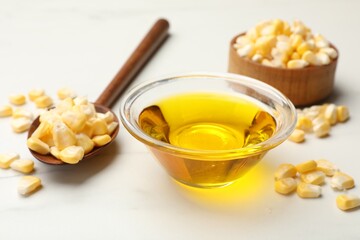 Corn oil and kernels on white table, closeup