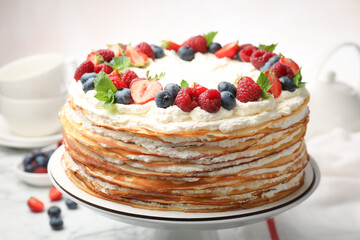 Delicious crepe cake with fresh berries on white table, closeup