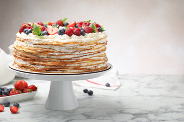 Delicious crepe cake with fresh berries on white marble table, space for text