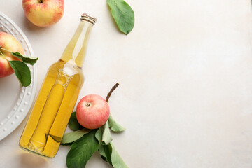 Delicious cider in glass bottle and apples with green leaves on beige table, flat lay. Space for text