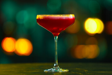 Glass of alcoholic cocktail on table against blurred background