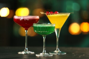 Glasses of alcoholic cocktails on table against blurred background