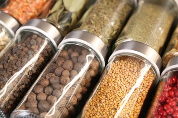 Different spices in glass jars as background, closeup